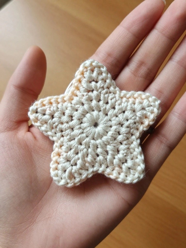 Crocheted cream-colored star resting on an open hand.