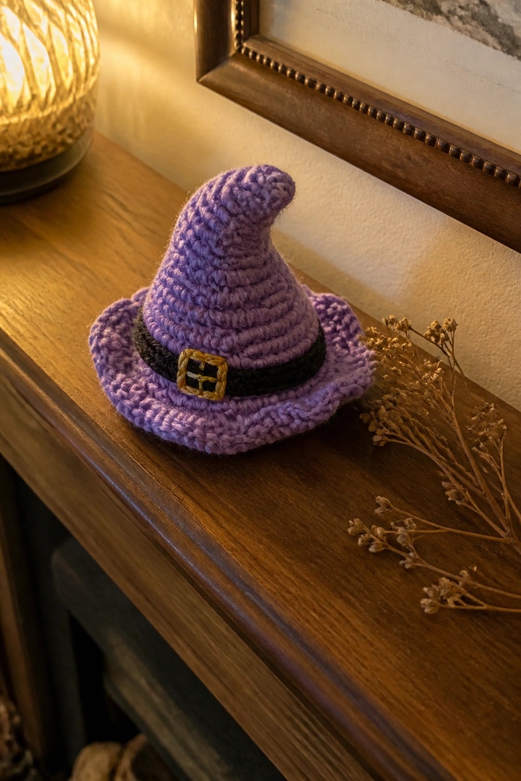 Purple crocheted witch hat with black band and gold buckle on wooden surface