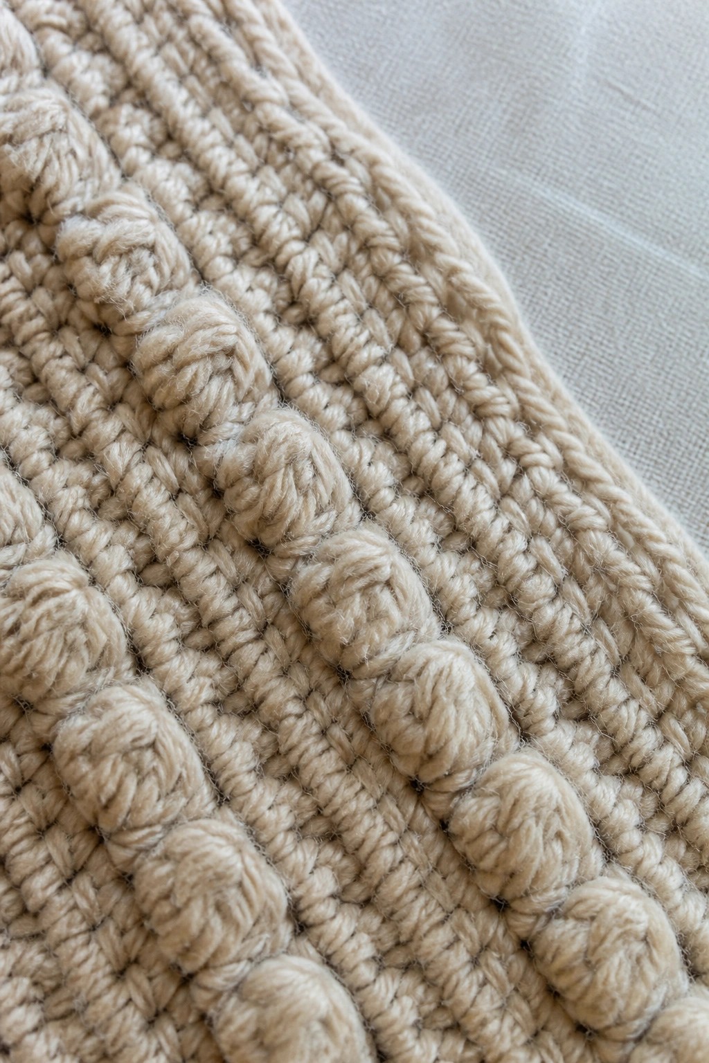 Beige chunky knit fabric with rows of raised bobble stitches in close-up