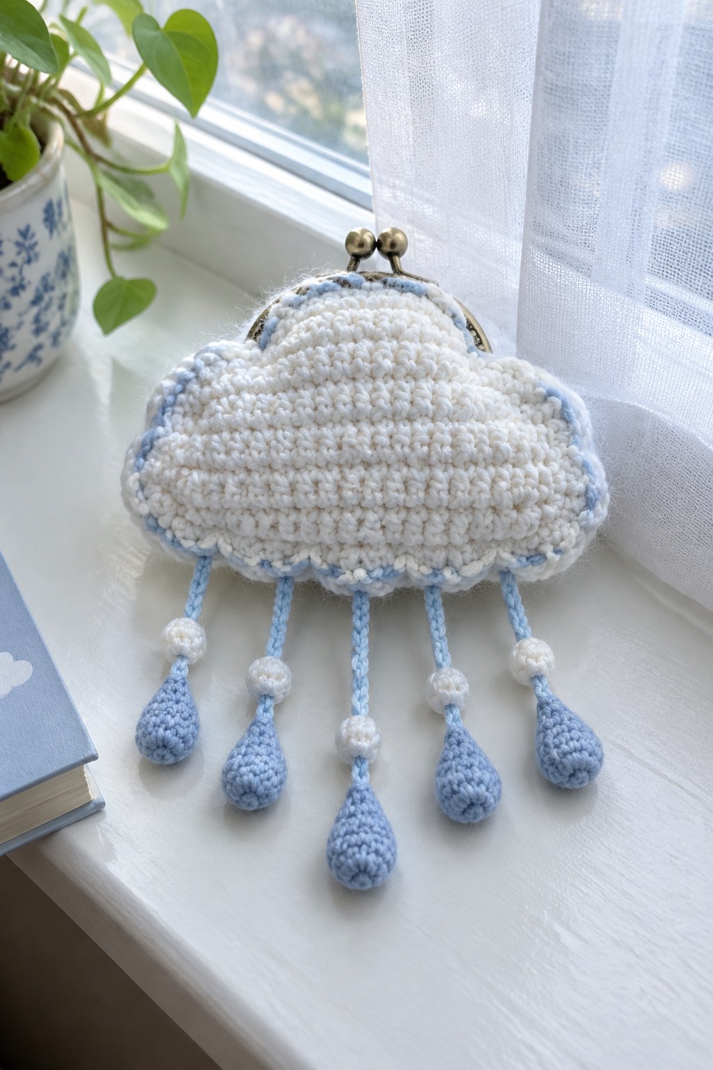 White crocheted cloud purse with blue trim and dangling raindrop tassels