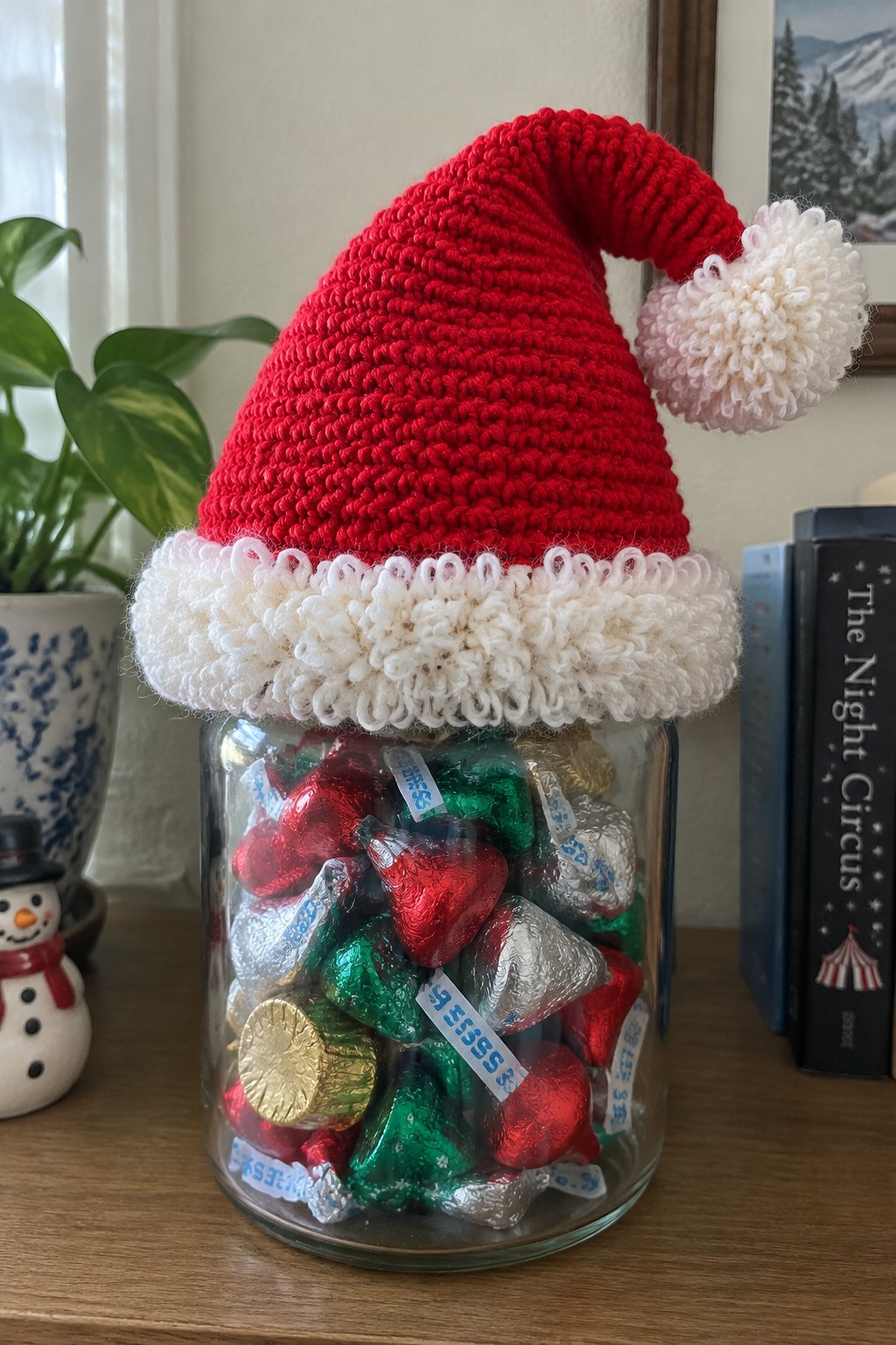 Glass jar of Hershey's Kisses topped with red knitted Santa hat and white pom-pom