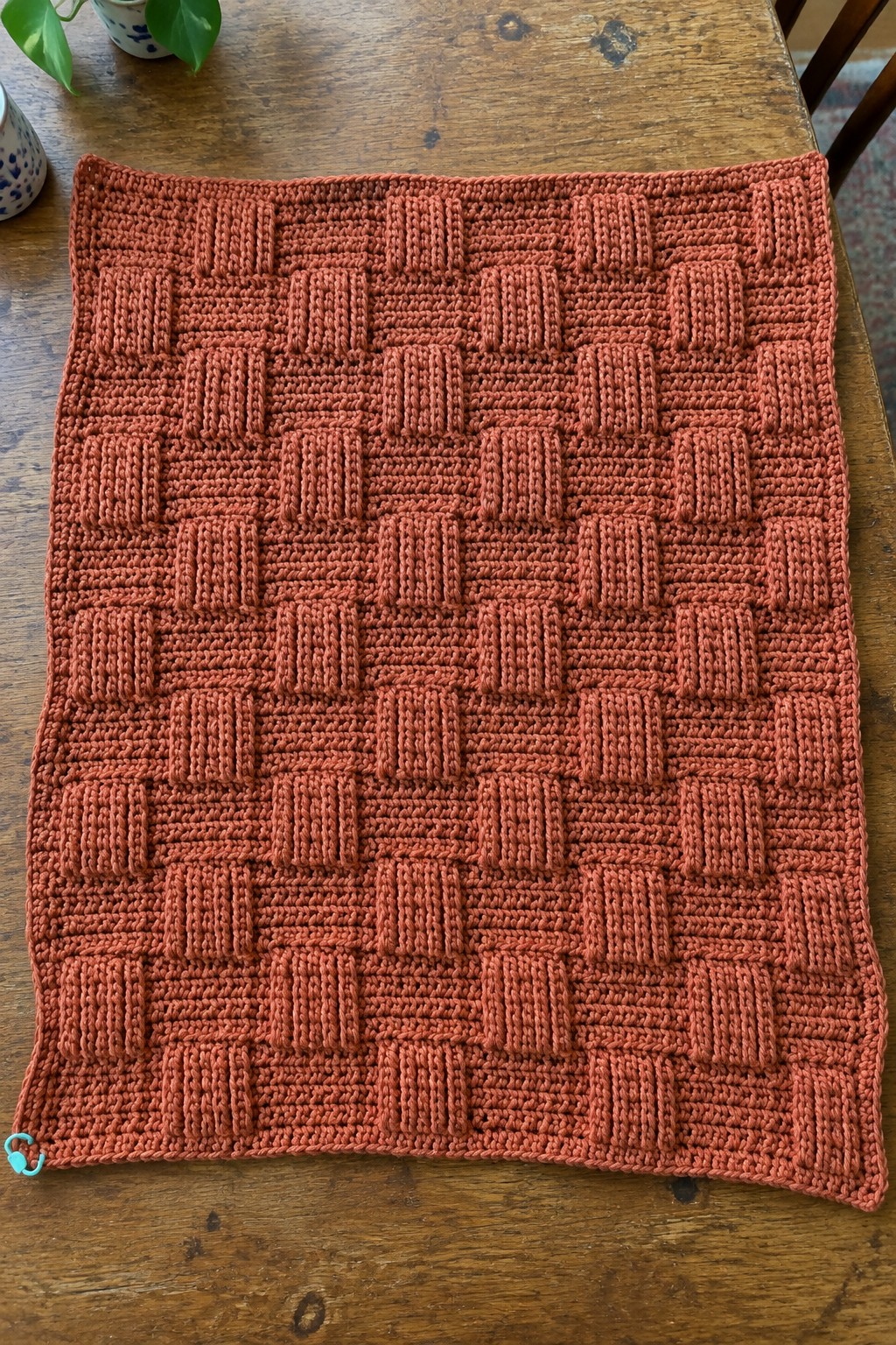Orange knitted blanket with basketweave texture on wooden table