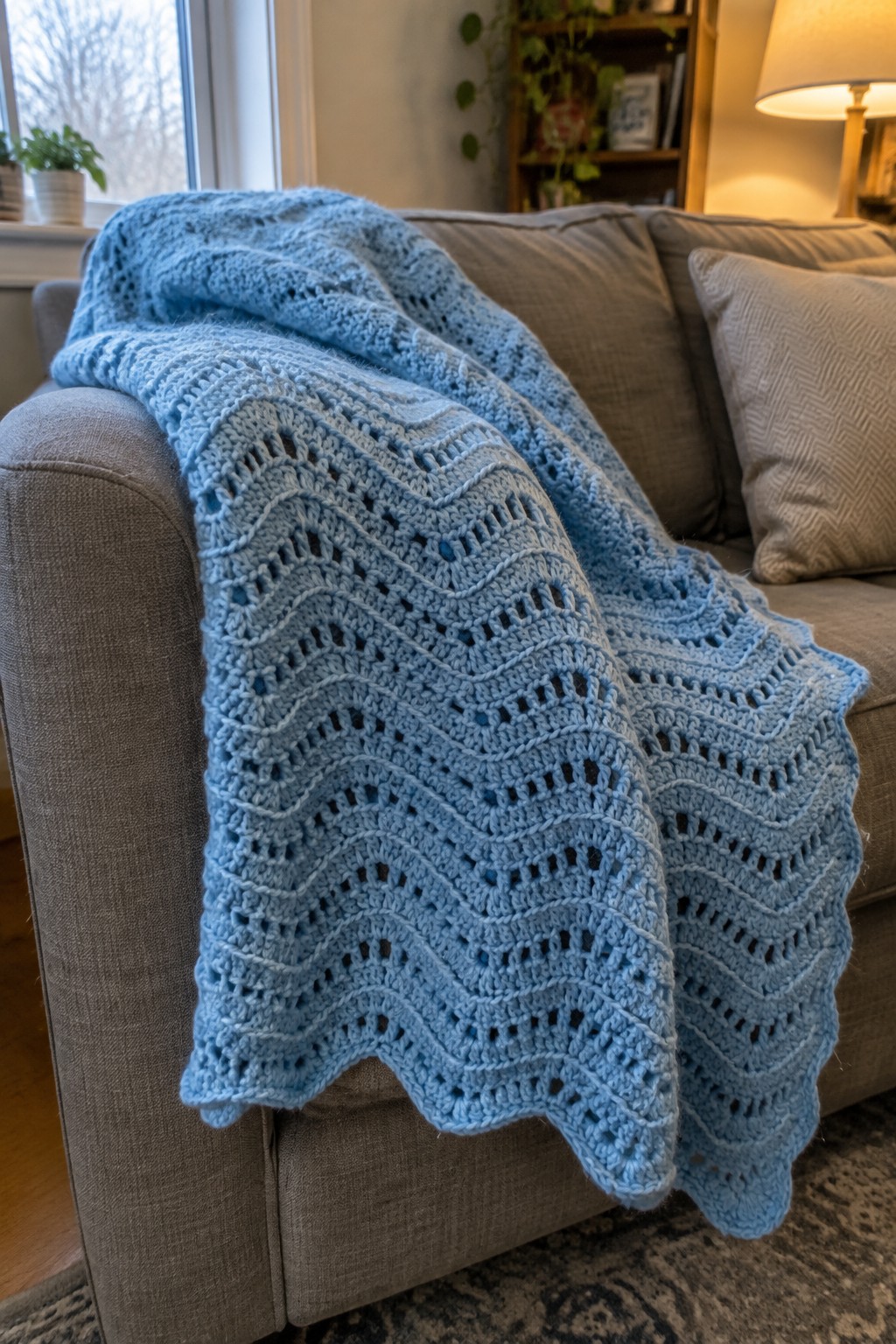 Light blue lacy crocheted blanket draped over gray living room couch
