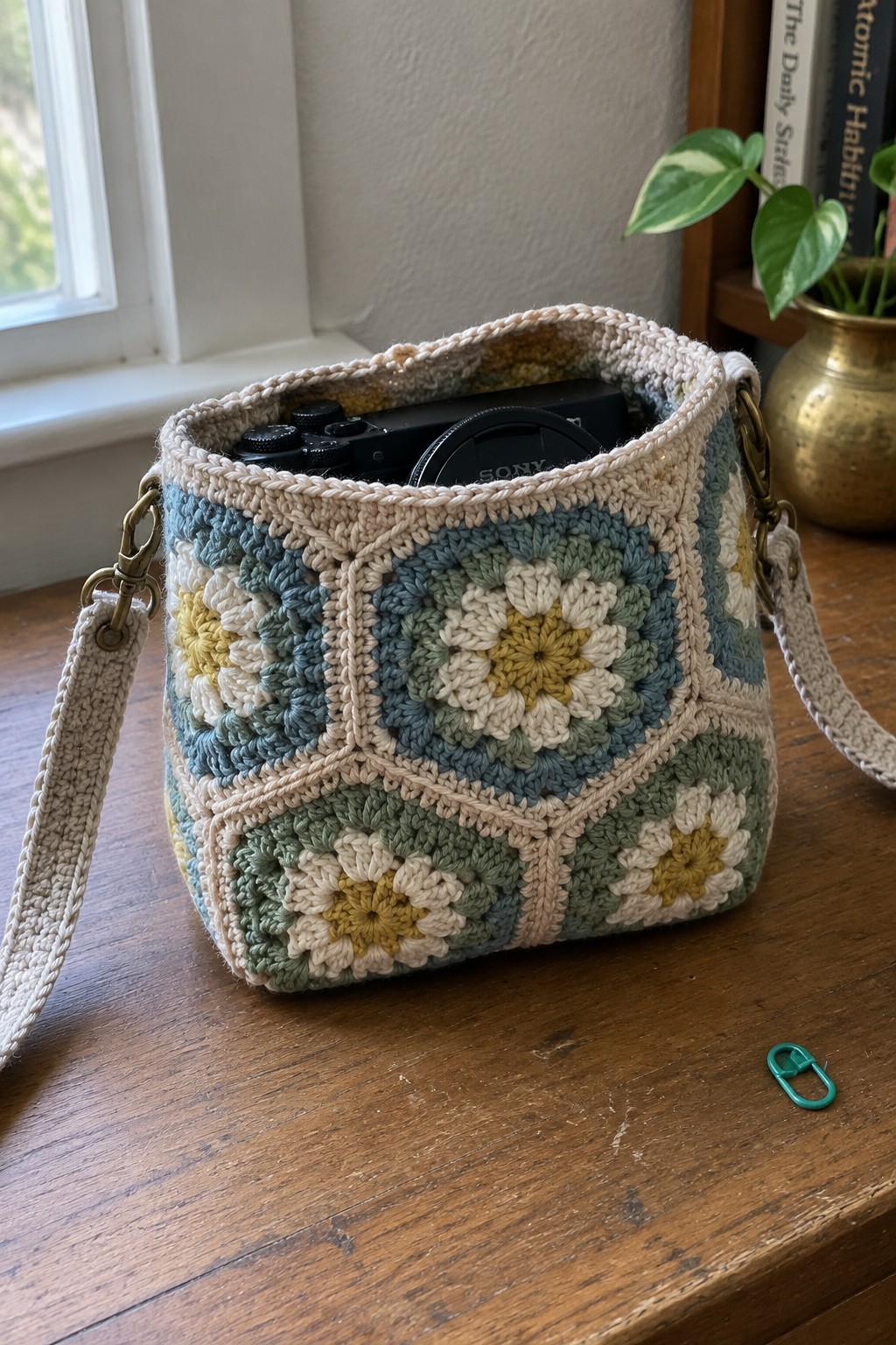 Colorful crocheted granny square bag holding a black Sony camera on wooden table.