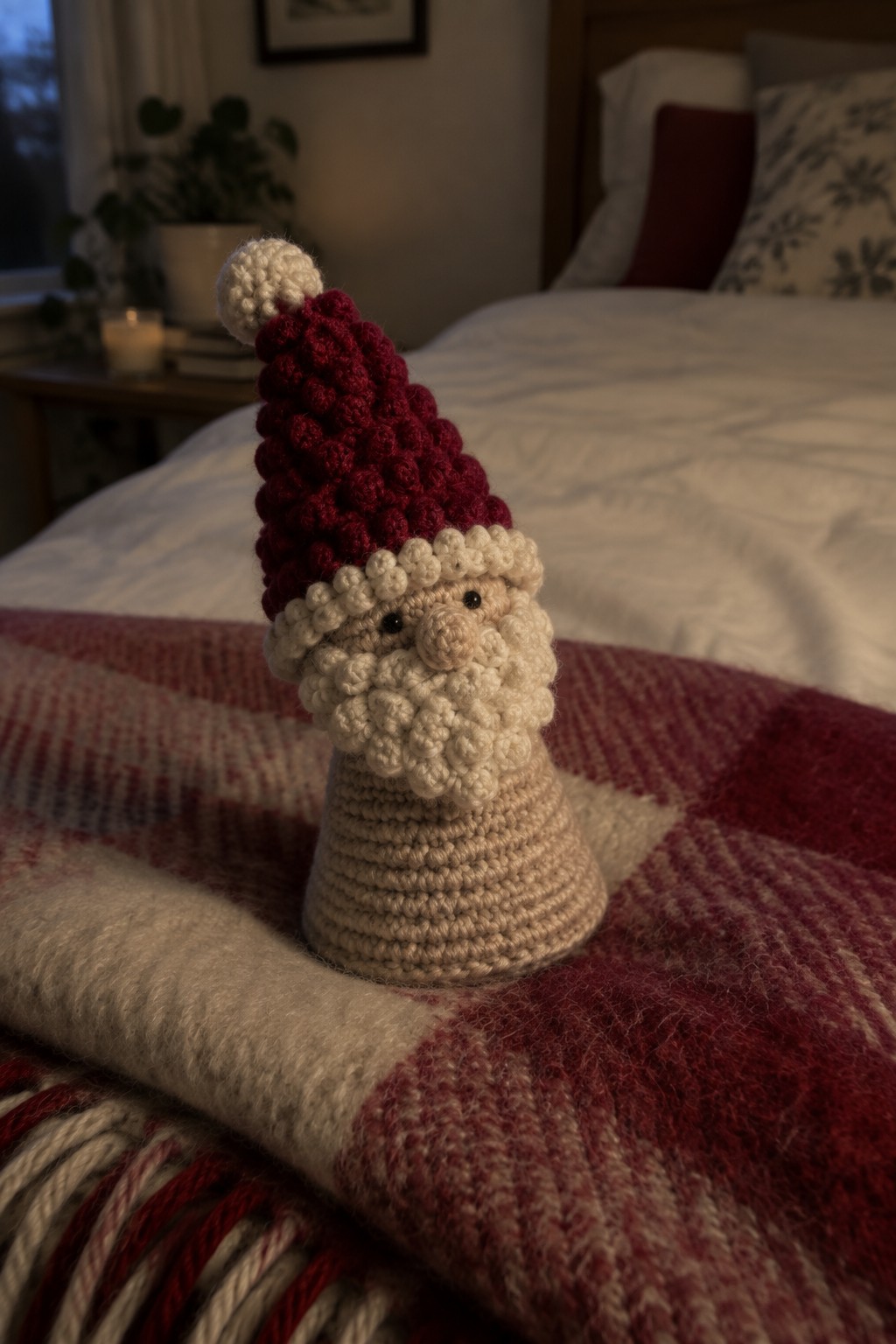 Crocheted Santa with red hat and white beard on red plaid blanket