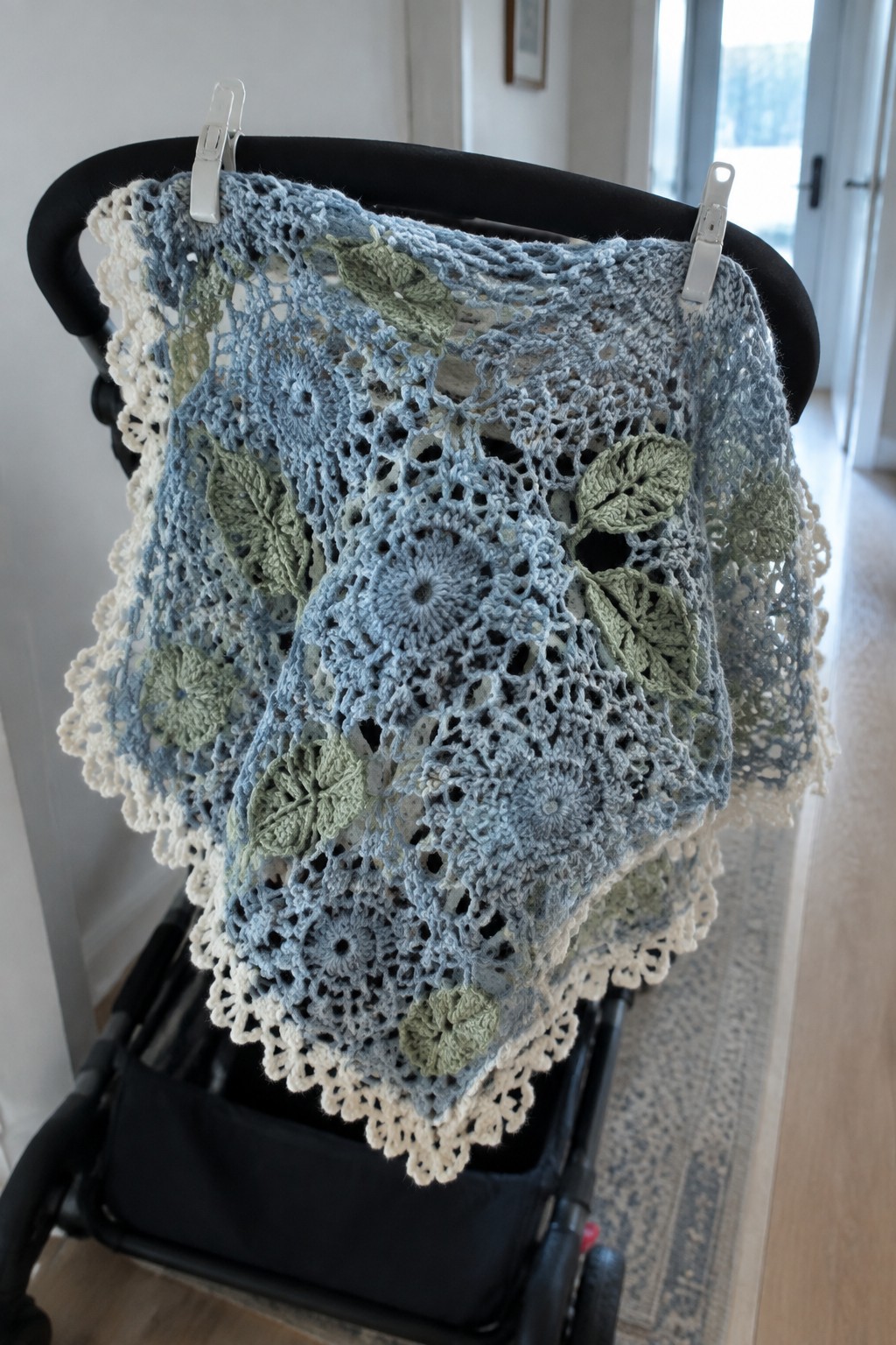 Blue and green floral crocheted blanket draped over a black stroller.