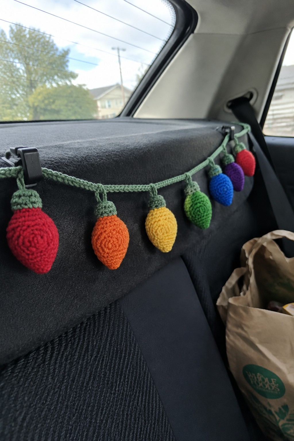 Crocheted multicolored Christmas lights clipped across a dark car backseat