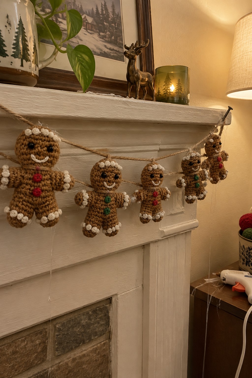 Crocheted gingerbread men garland hanging on white fireplace mantel with holiday decor