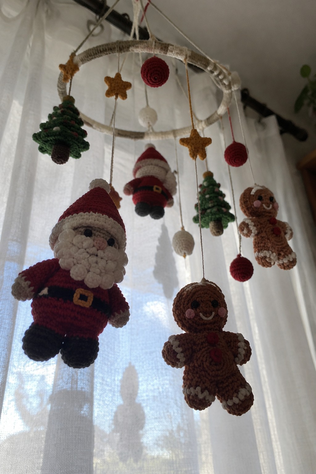 Crocheted Christmas mobile with Santa, gingerbread men, trees, stars, and baubles.