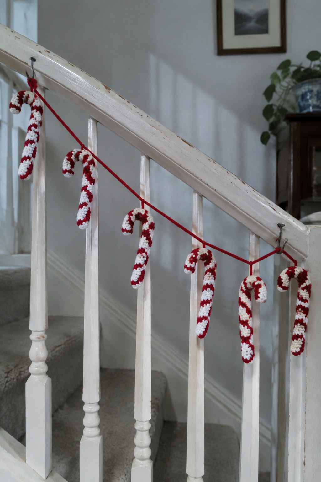 Red and white crocheted candy canes strung along a white staircase railing.