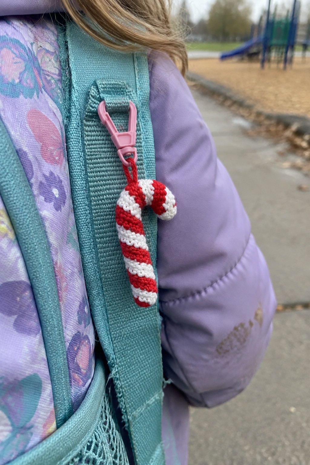 Purple jacket with butterfly backpack and crocheted red-white candy cane on pink clip