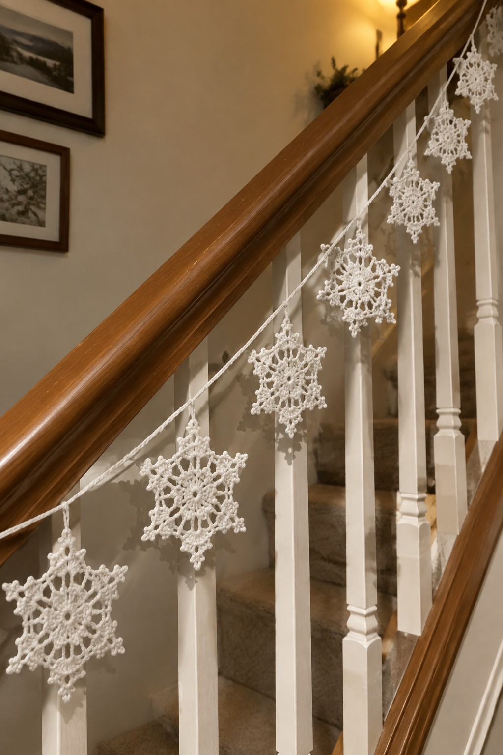 White crocheted snowflakes strung along a wooden staircase railing.