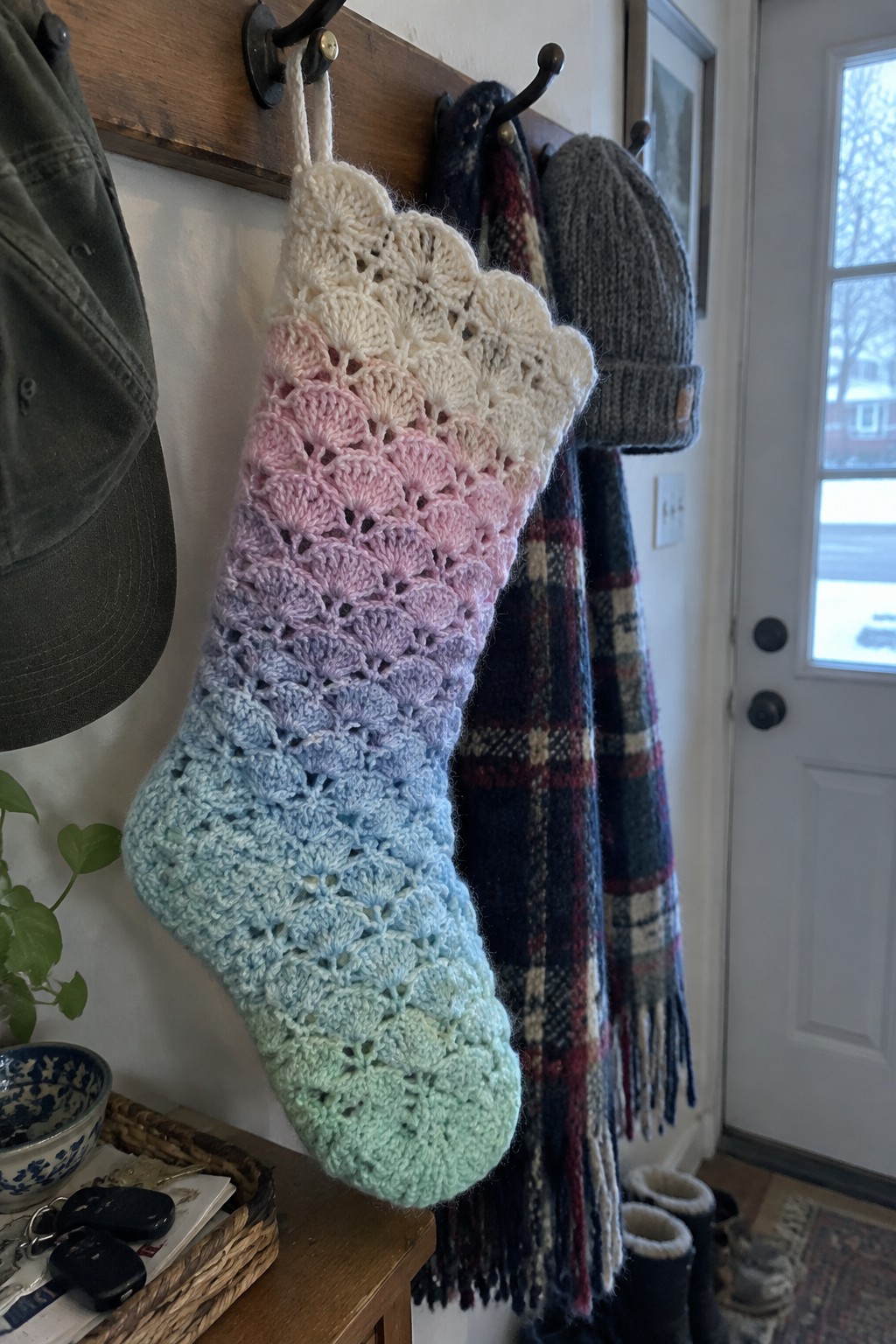 Pastel ombre crocheted stocking with scalloped edge on wooden coat rack