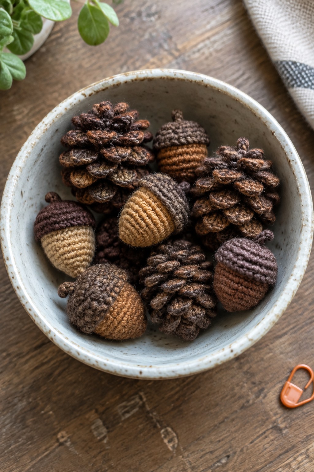 Bowl of crocheted brown acorns and pinecones on rustic wooden table