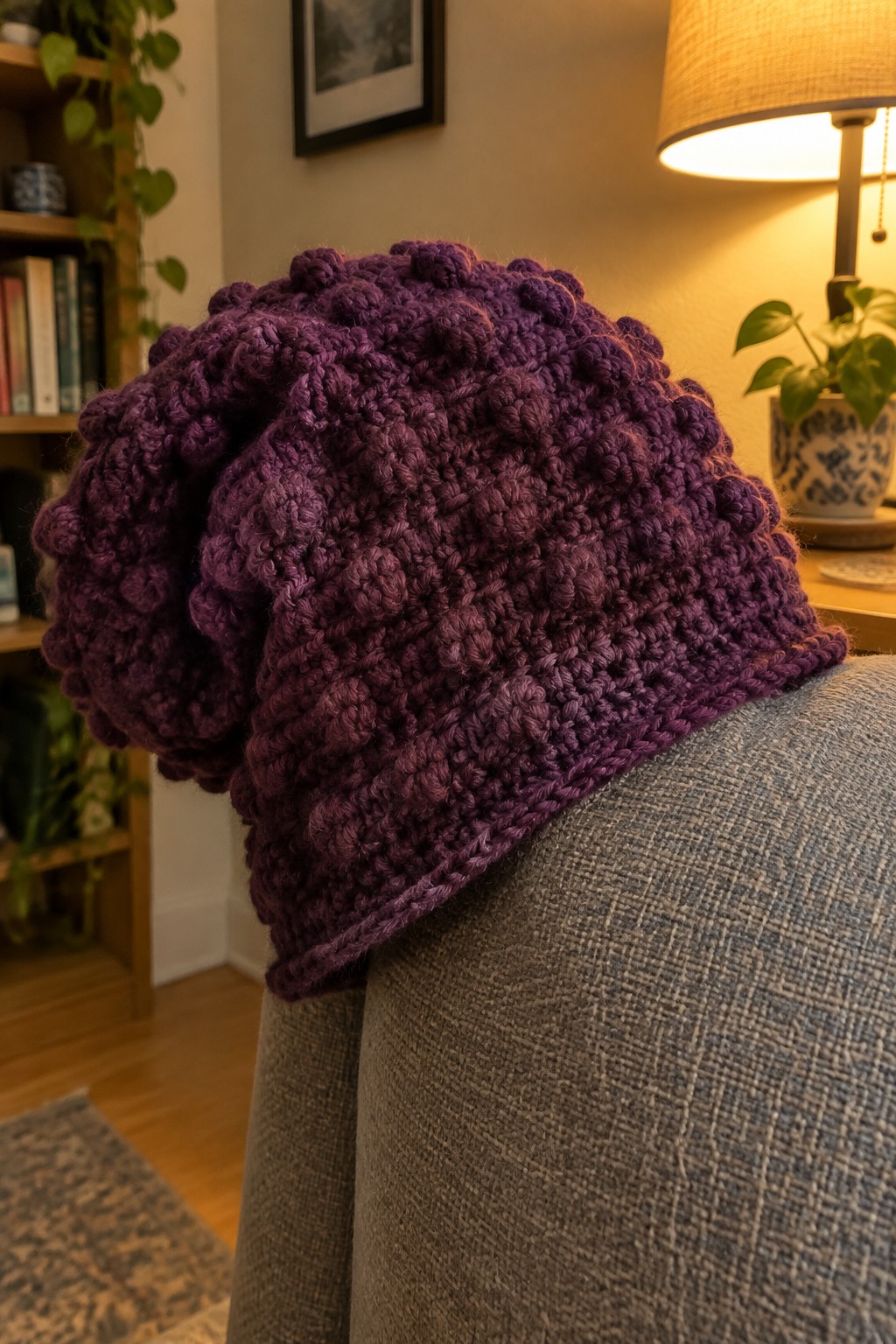 Purple bobble-knit slouchy hat resting on gray upholstered chair arm