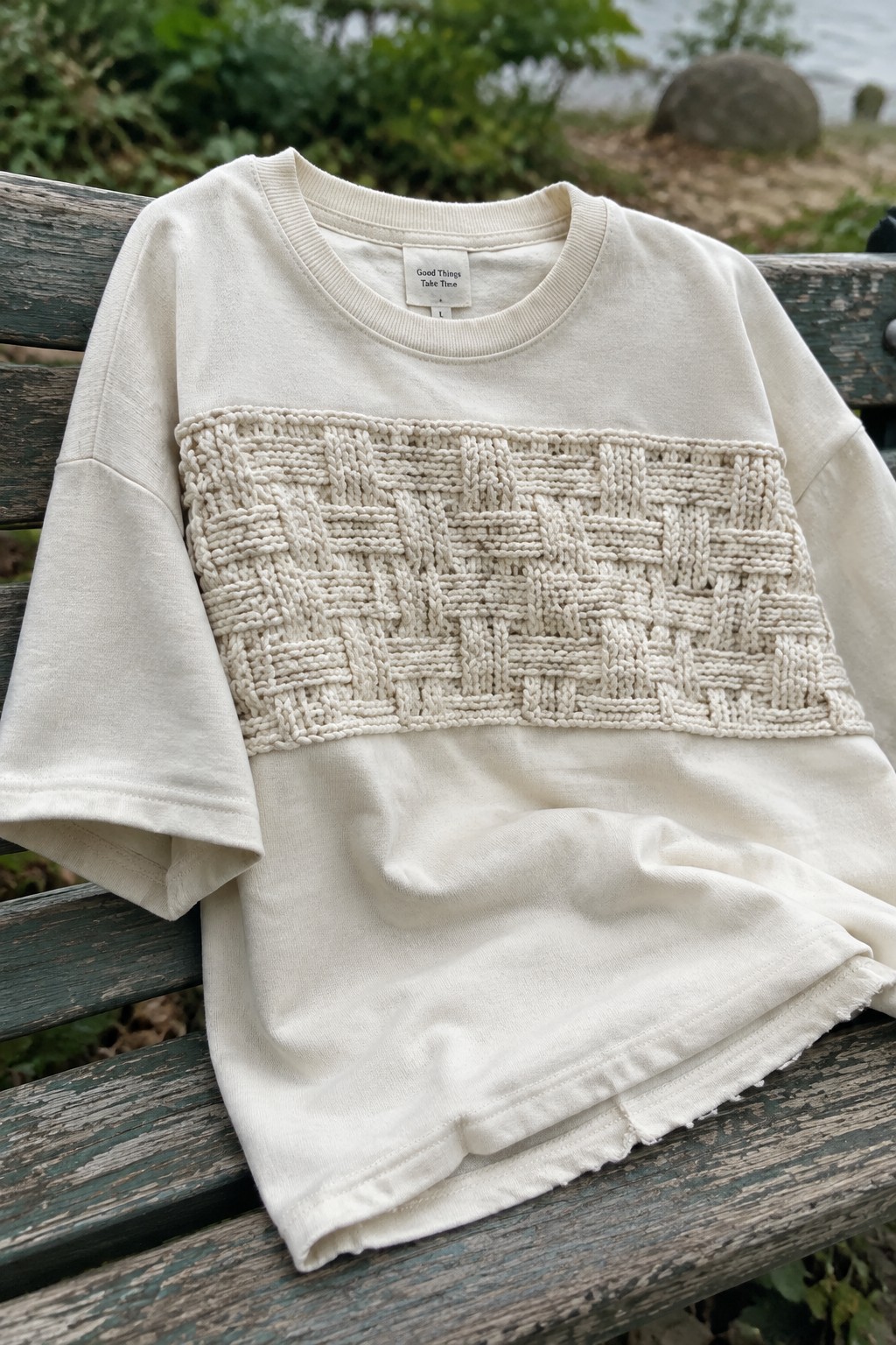 Cream t-shirt with basket-weave knit panel on weathered wooden bench outdoors