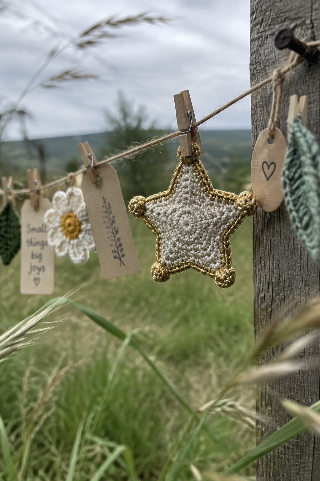 Crocheted white star with gold trim clipped to twine on wooden post outdoors