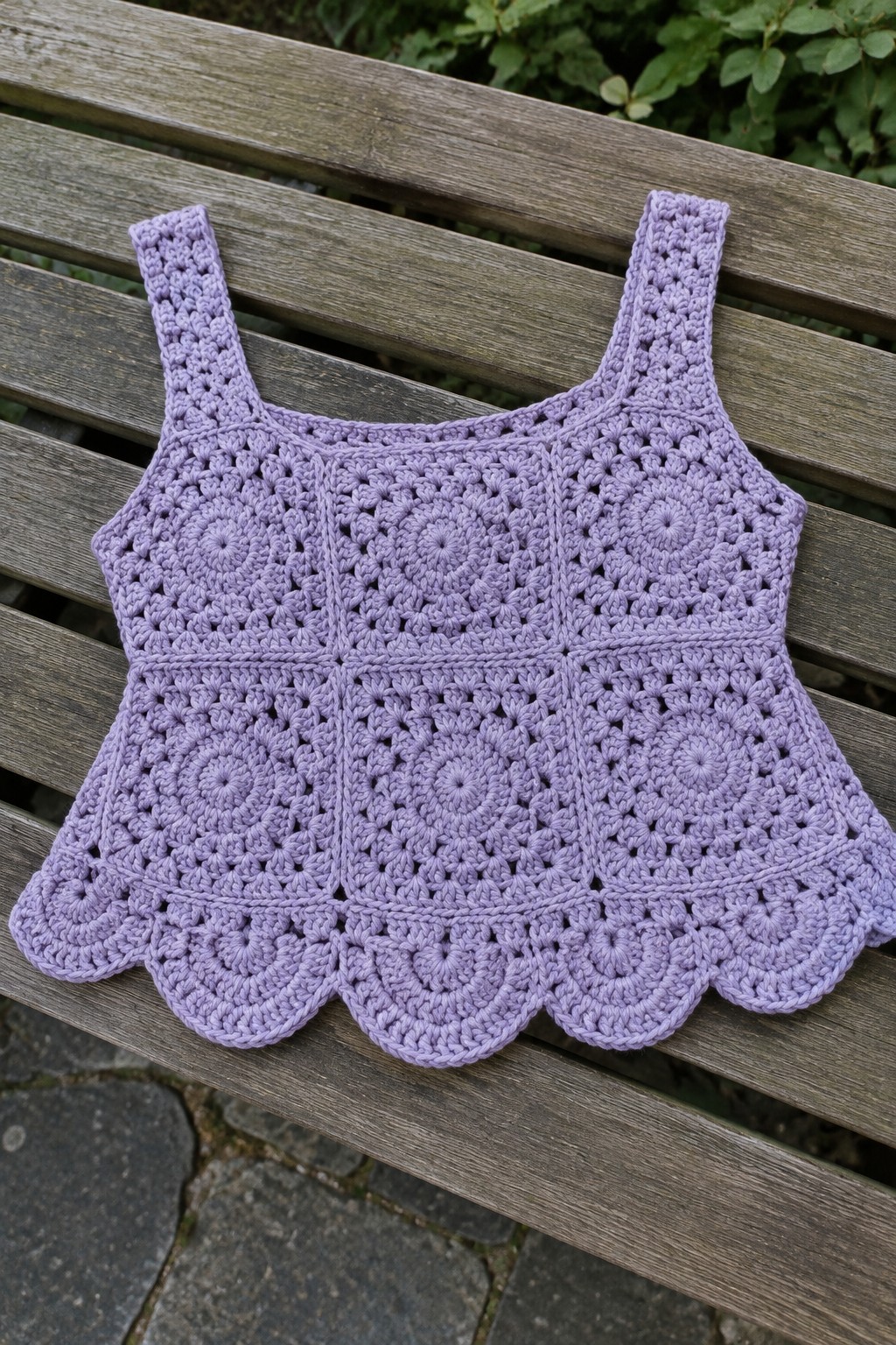 Lavender crocheted tank top with circular motifs on wooden bench