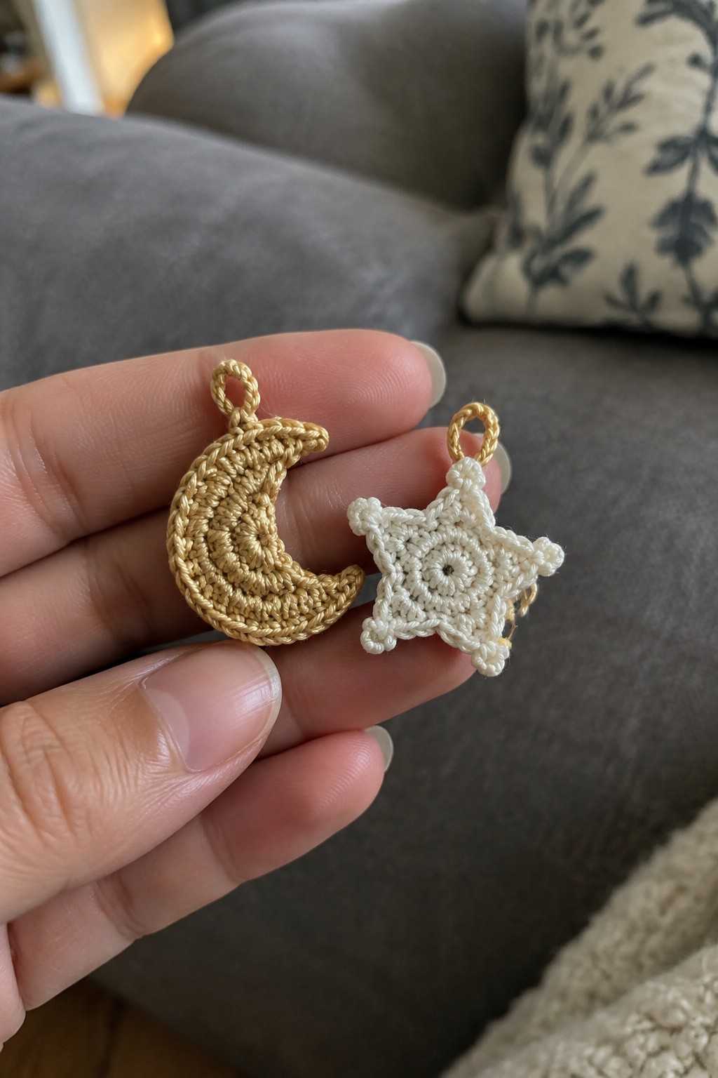 Hand holding crocheted gold crescent moon and white star charms