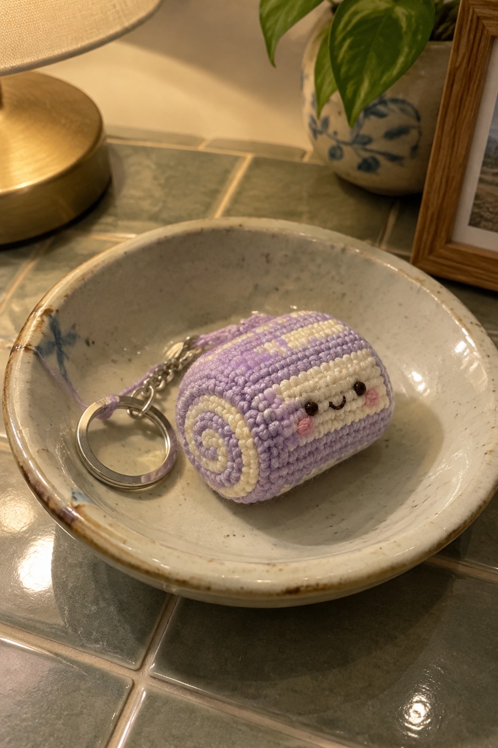 Purple and white striped crocheted roll keychain with cute face in ceramic bowl