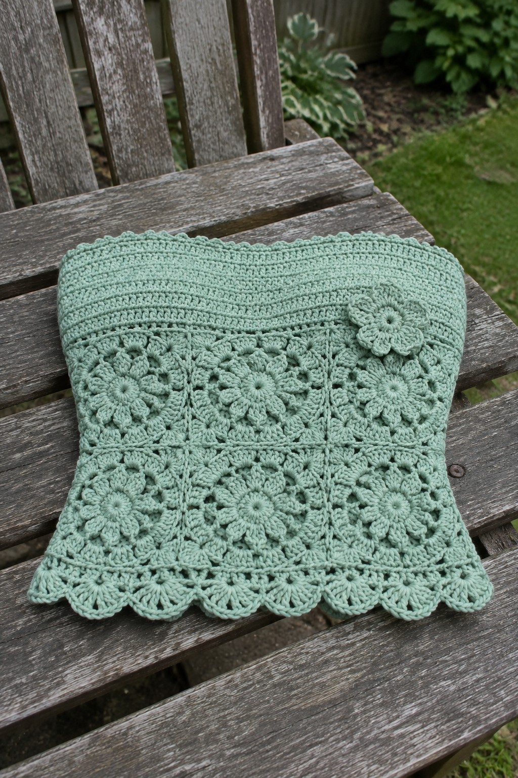 Mint green crocheted square with floral motifs on weathered wooden bench