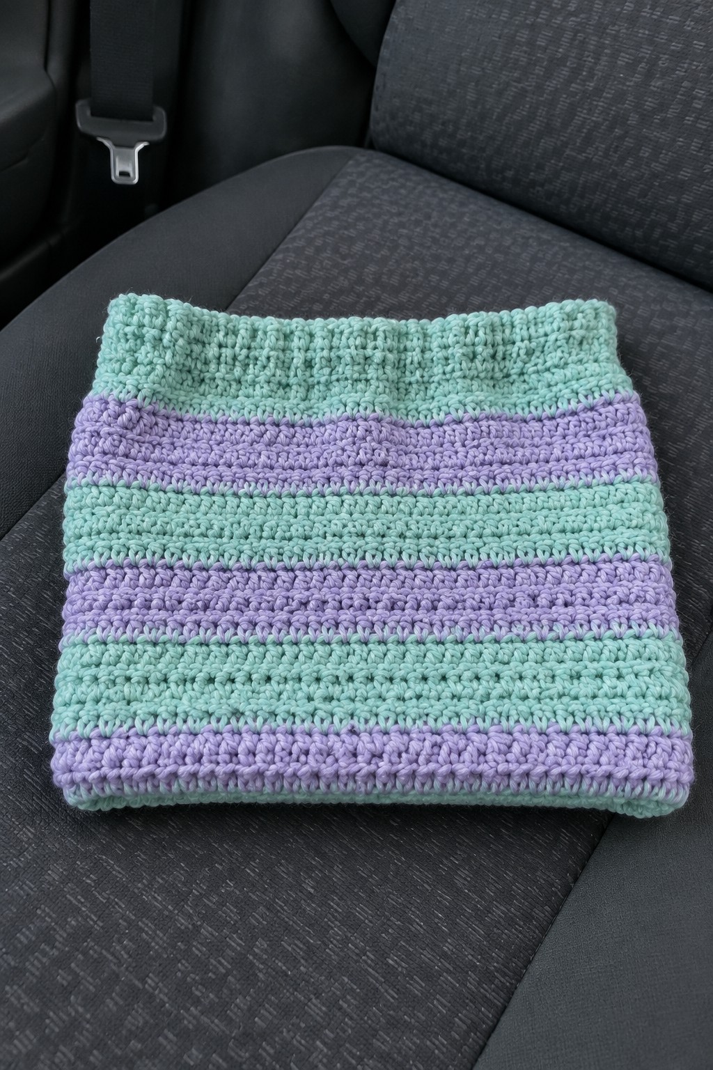 Striped mint green and lavender crochet cowl on gray car seat.